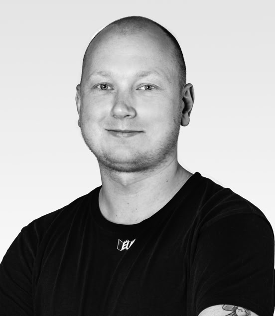 A black and white portrait of a smiling person with short hair, wearing a dark shirt.